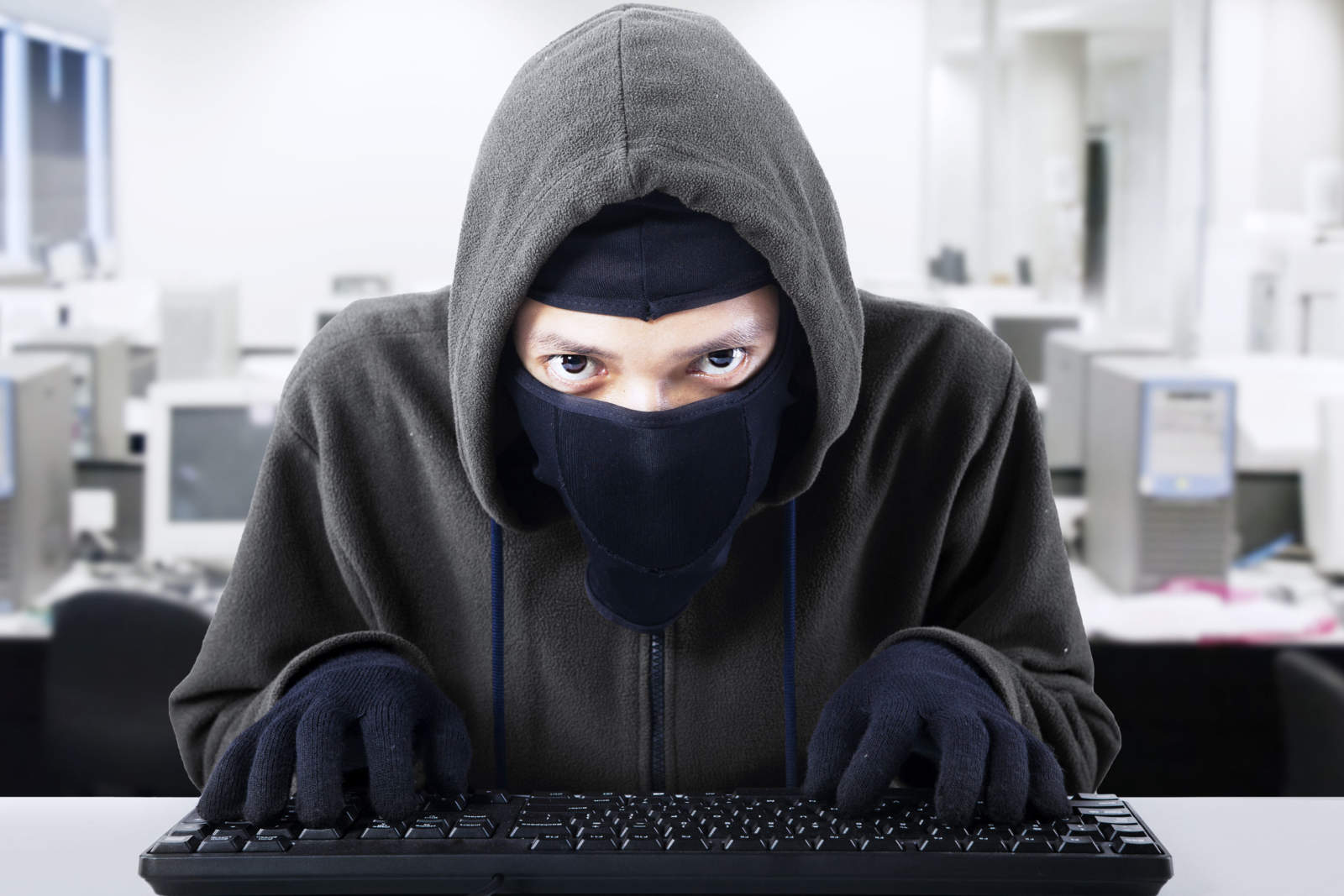 ad fraud revenue thief sitting at computer keyboard
