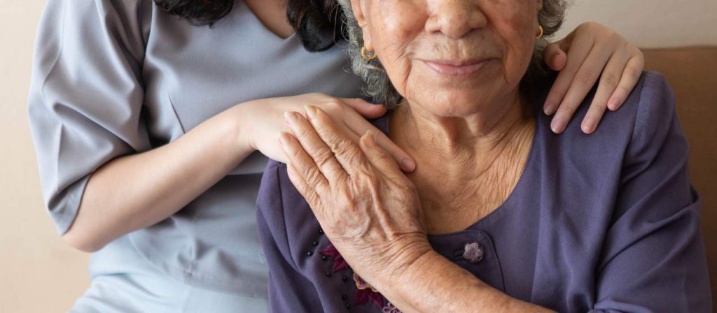 An elderly woman holding a nurse's hand