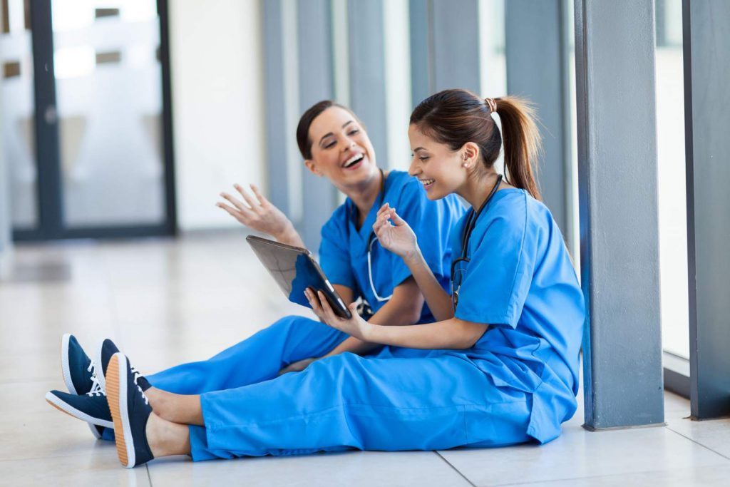 Two nurses sitting on the floor and laughing together
