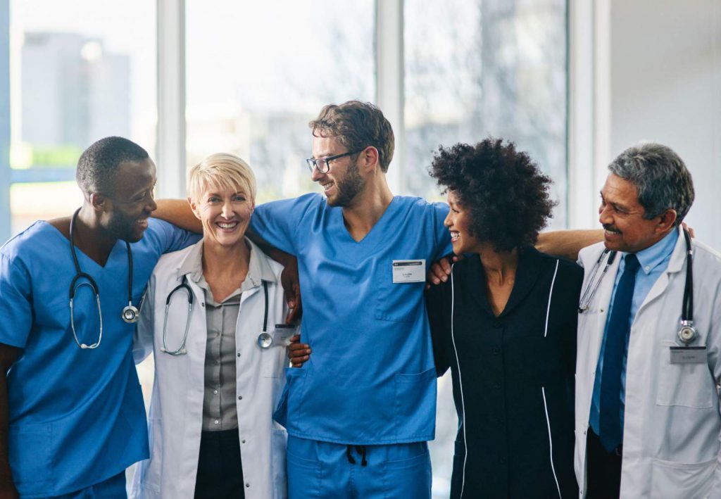 A group of healthcare workers smiling with their arms around each other