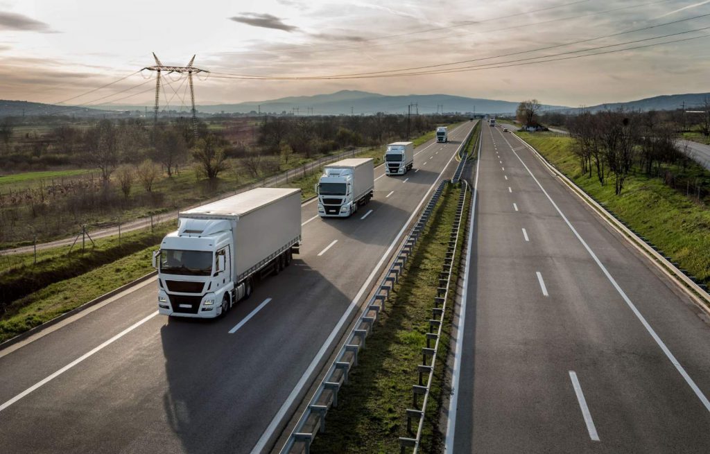 A caravan of trucks driving on a highway