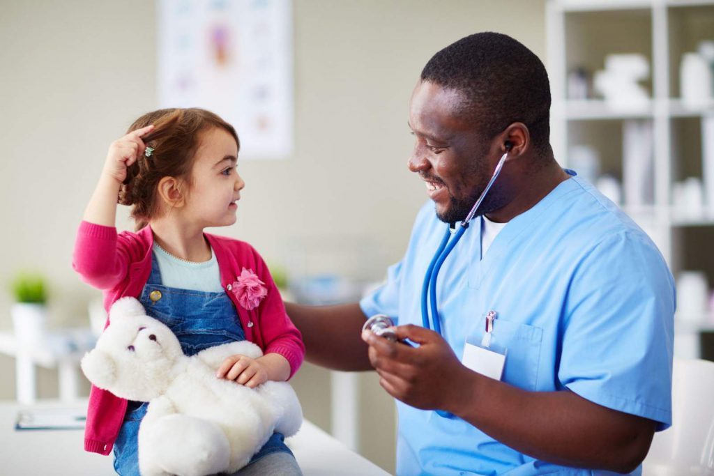 A male nurse smiling at a pediatric patient