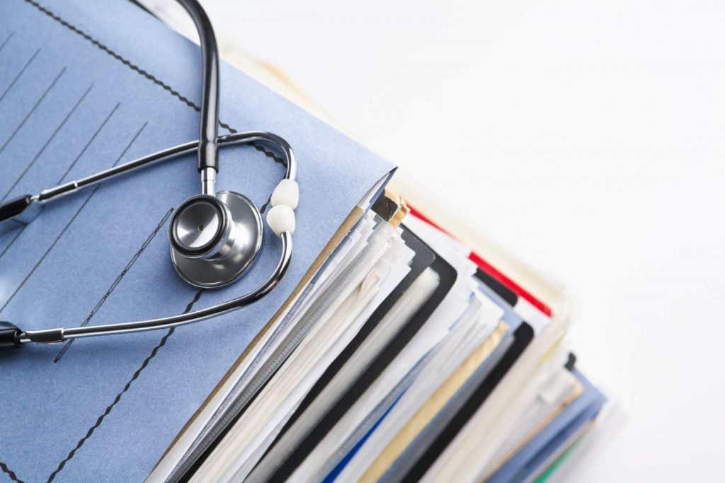 A stethoscope sitting on a stack of medical records