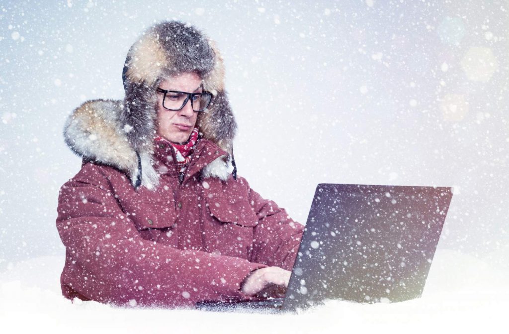 Man using laptop in a snow storm, representing cold emails