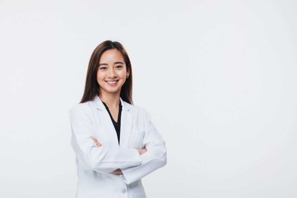 Female physician standing in front of a white background with her arms crossed and smiling