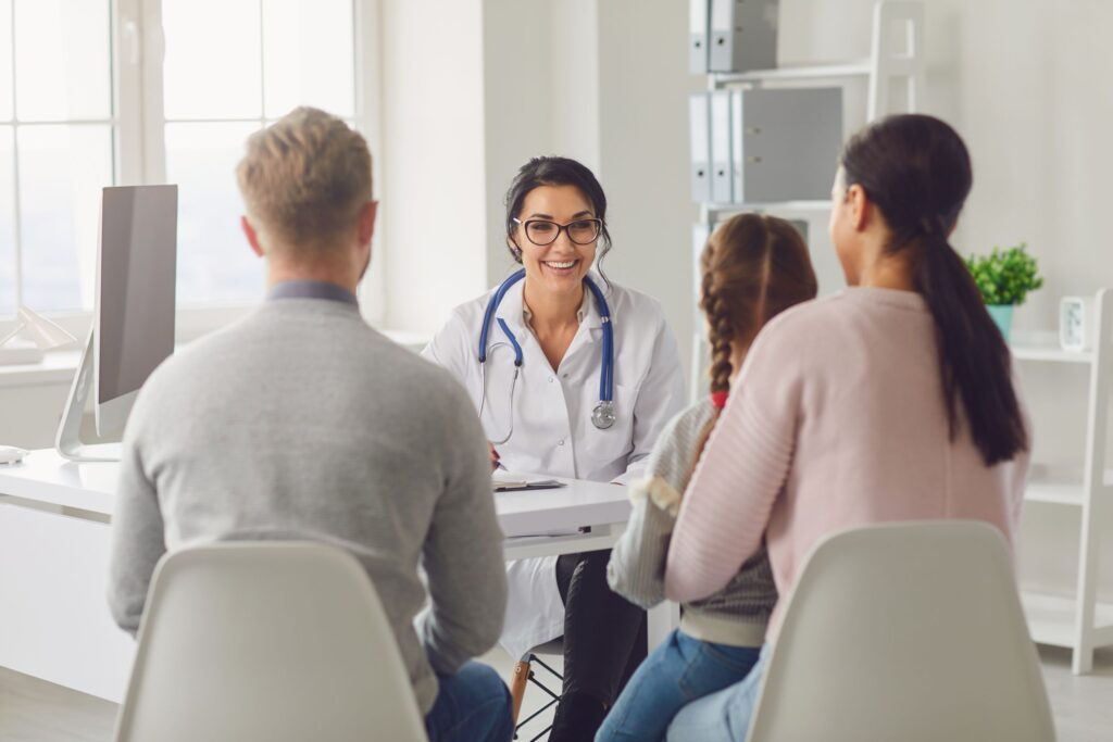 A female physician meeting at a table with two parents and their daughter