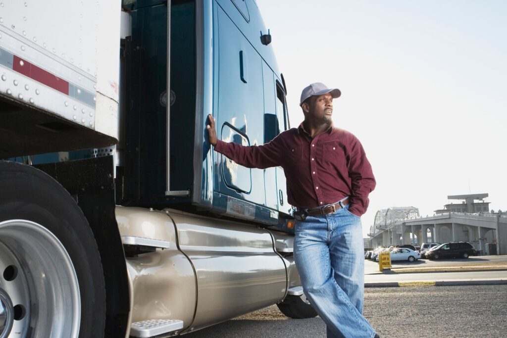 A truck driver standing and leaning against the side of his truck