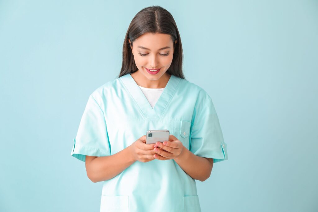 A nurse looking down at her phone and smiling