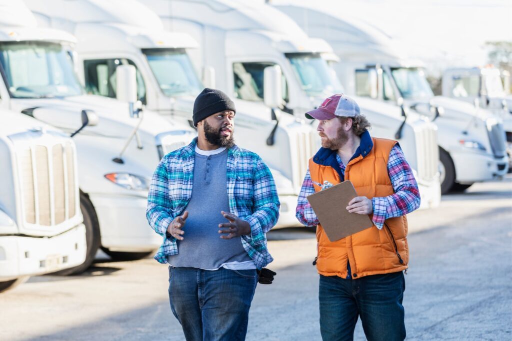 Two truck drivers walking and having a conversation in a parking lot