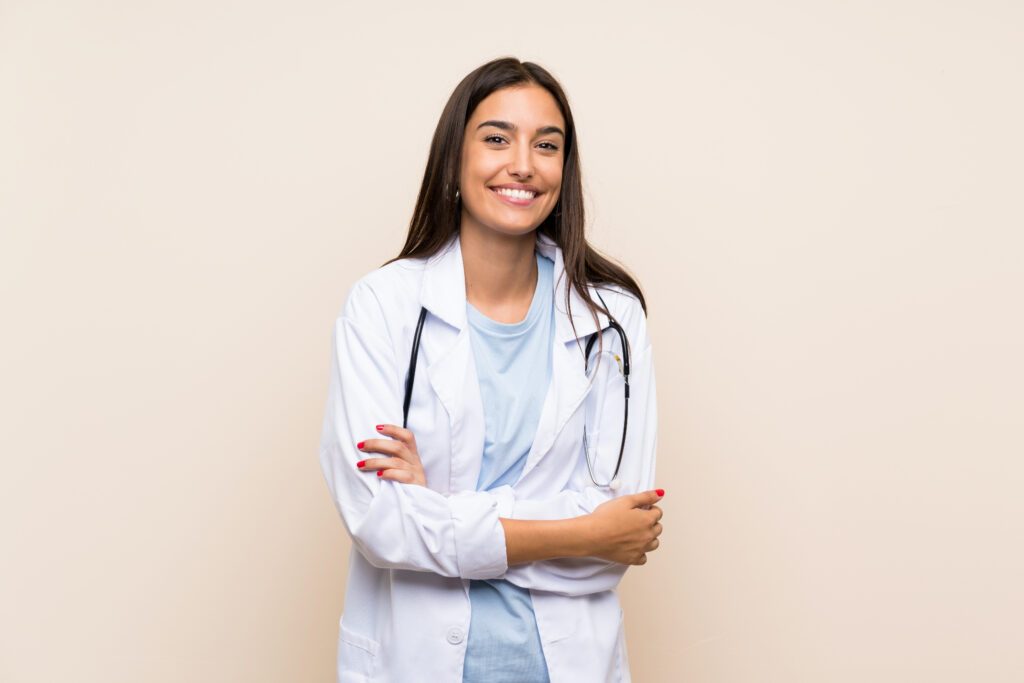 Young female doctor over isolated background laughing