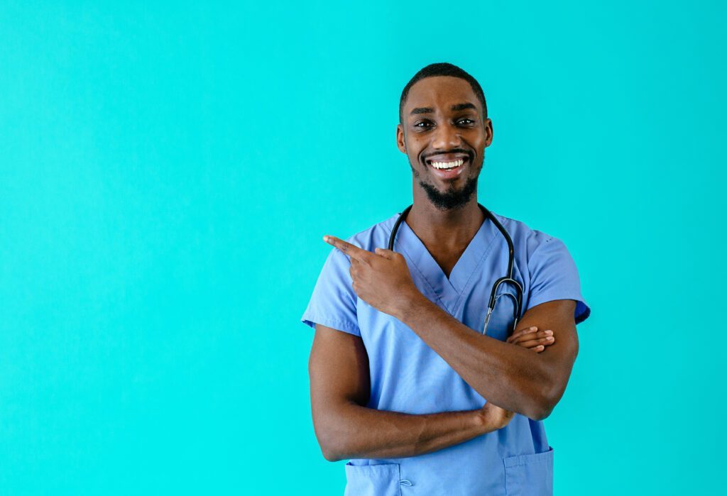 Portrait of a smiling male nurse pointing with finger to side