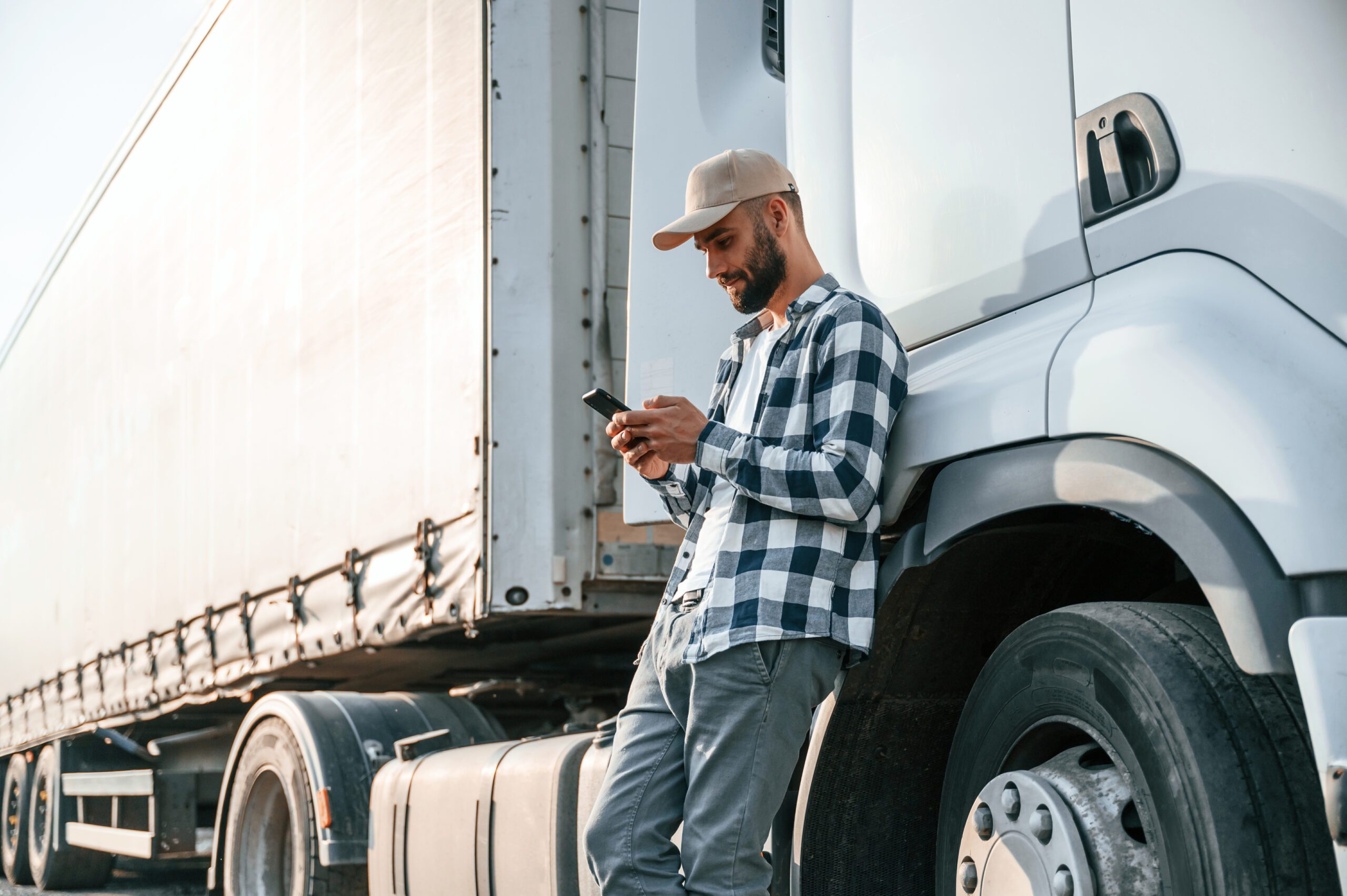 truck driver leaning on side of truck using phone