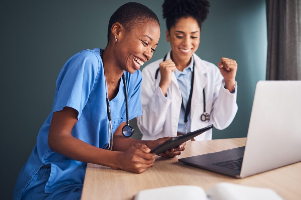 A physician and nurse looking at a computer and celebrating