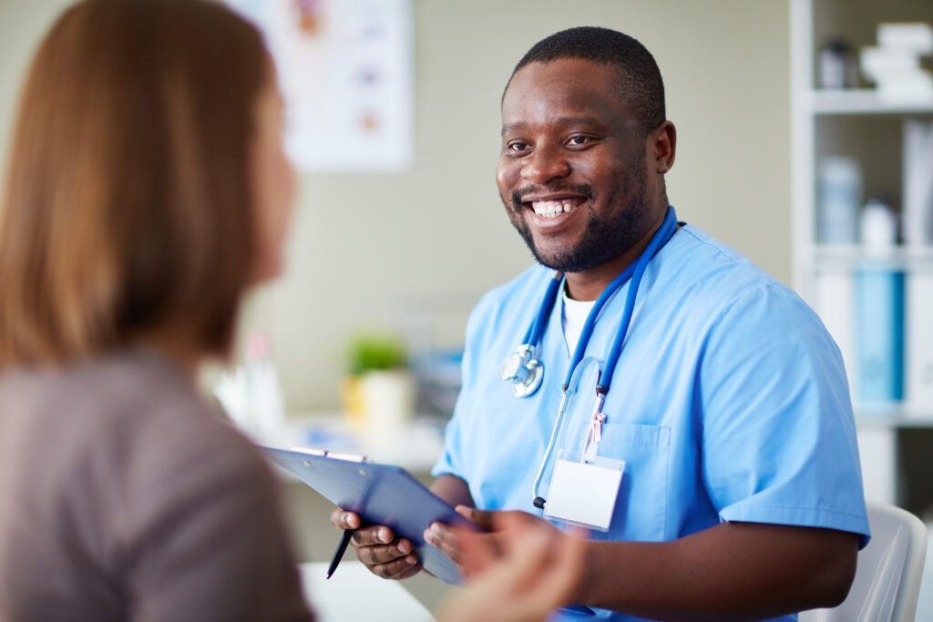 Male nurse holding a clipboard and smiling at a woman 