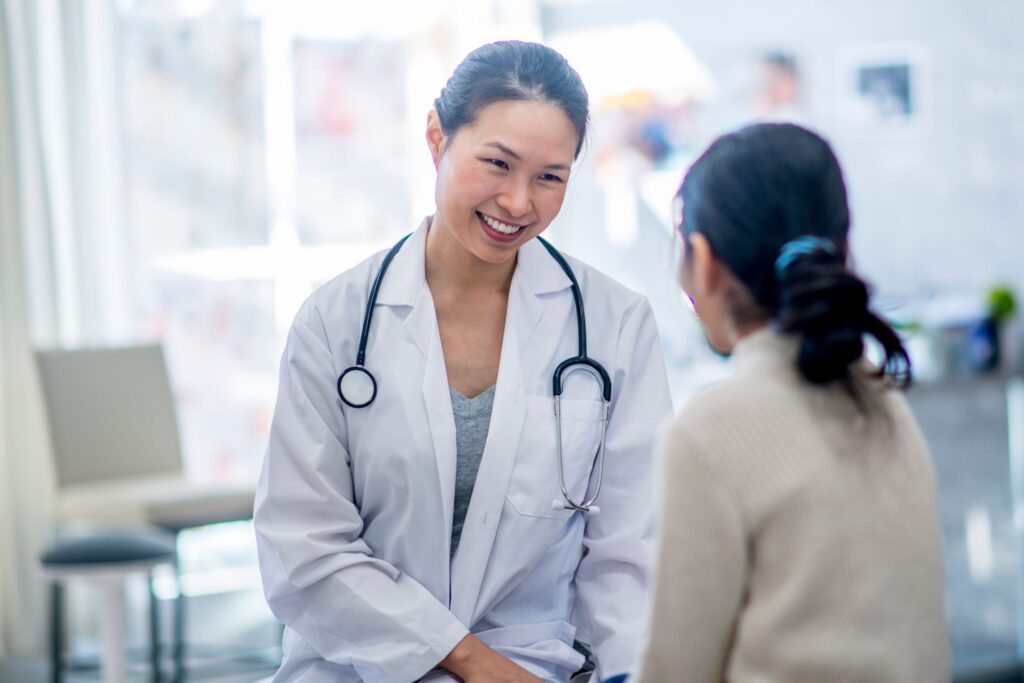 An Asian female doctor smiling at a patient