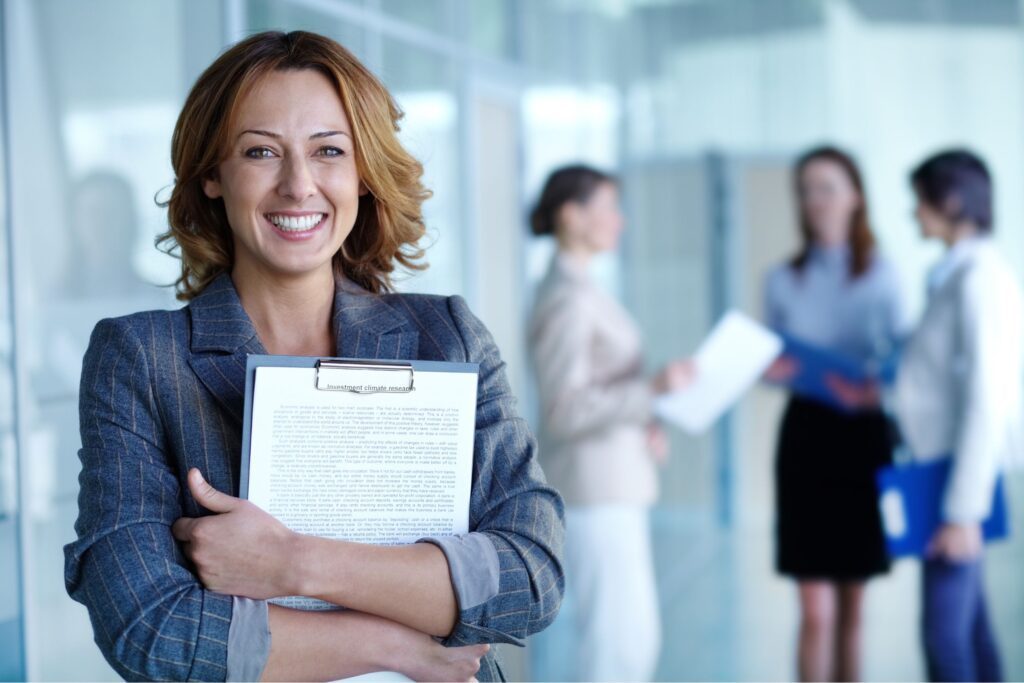 A woman holding a clipboard and smiling at the camera