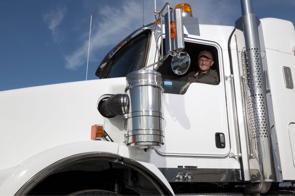 A truck driver sitting in his truck and looking out the window