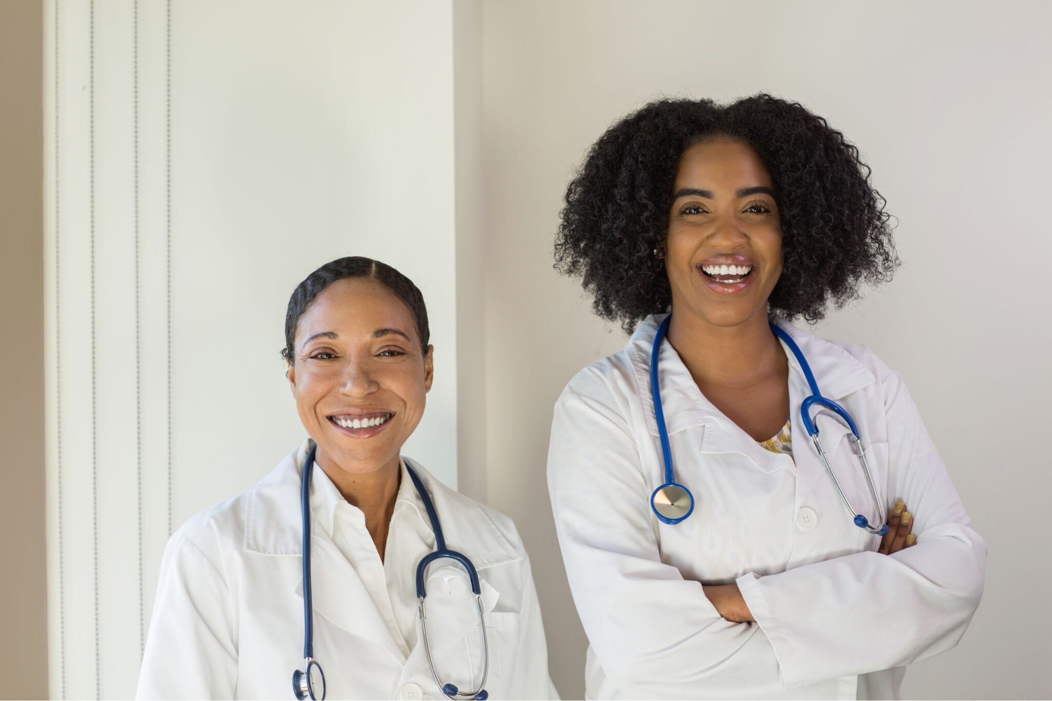 Two female doctors of color smiling at the camera