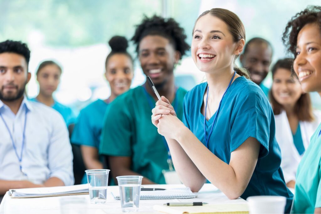 A group of nurses smiling and listening to a presentation 