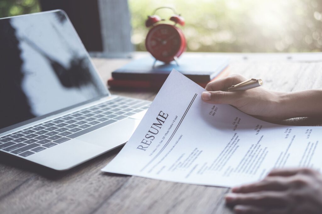 A person holding a resume and looking at the computer