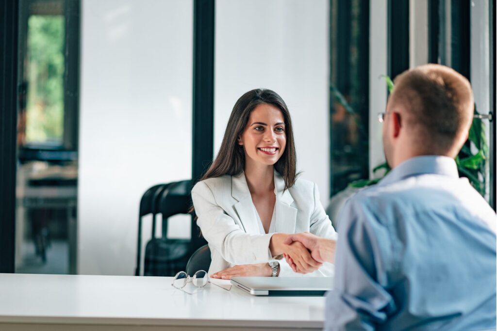 A woman and a man shaking hands during a job interview