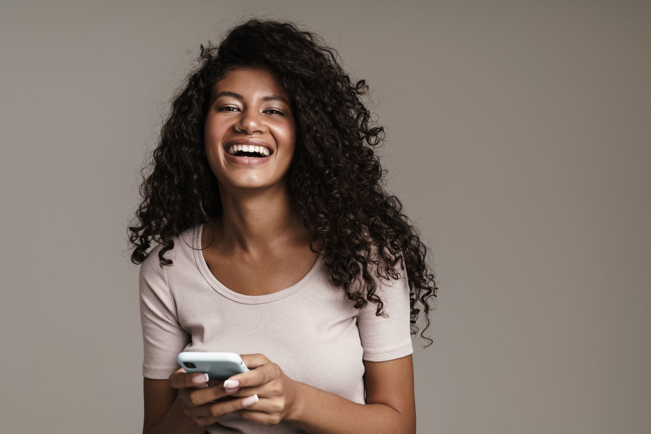 A woman texting and smiling at the camera