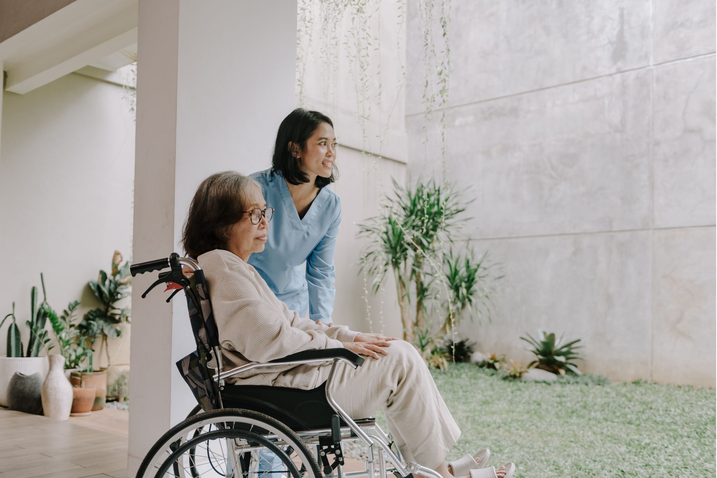 A female nurse wheeling a patient in her wheelchair