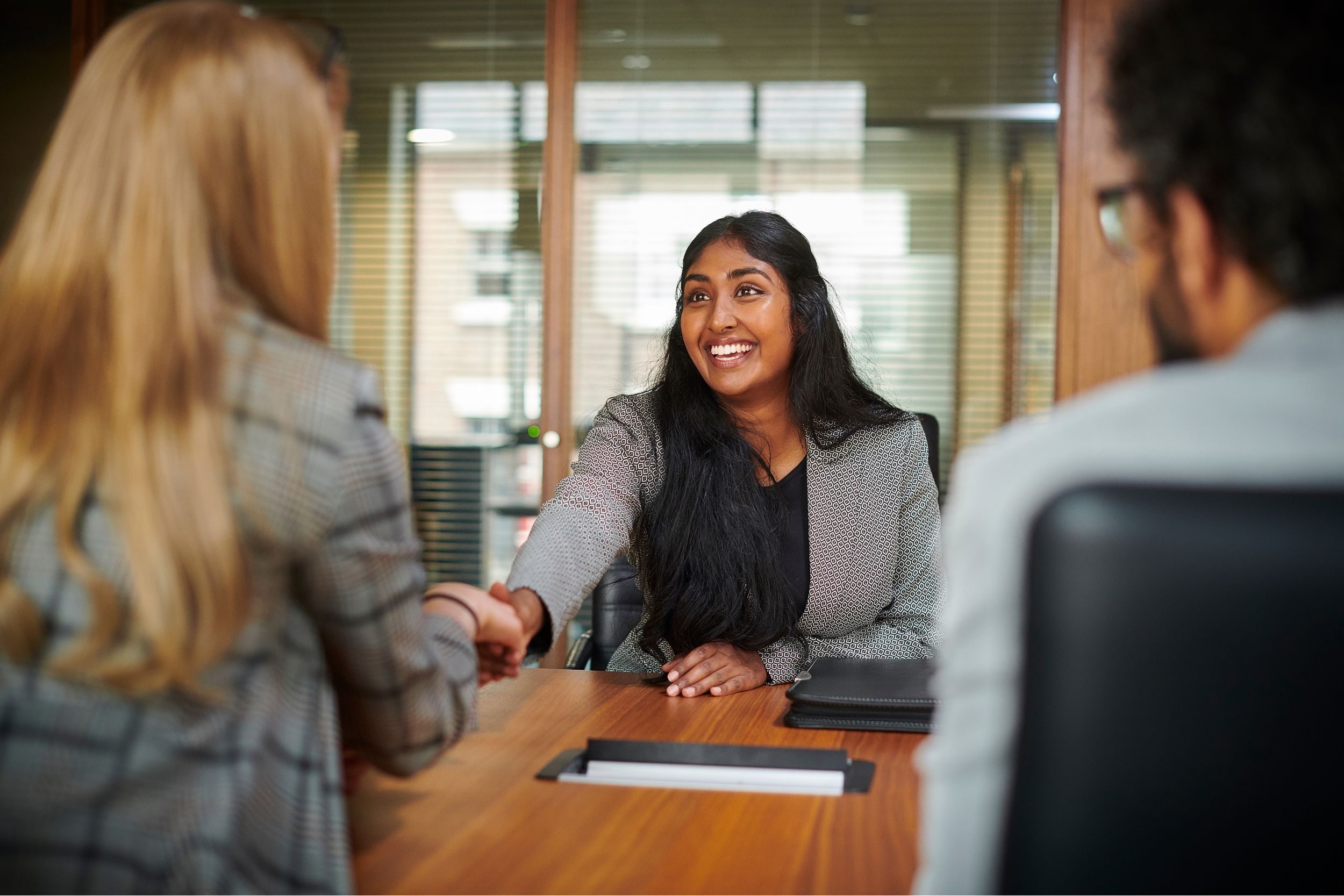 A woman shaking hands with two people during a job interview
